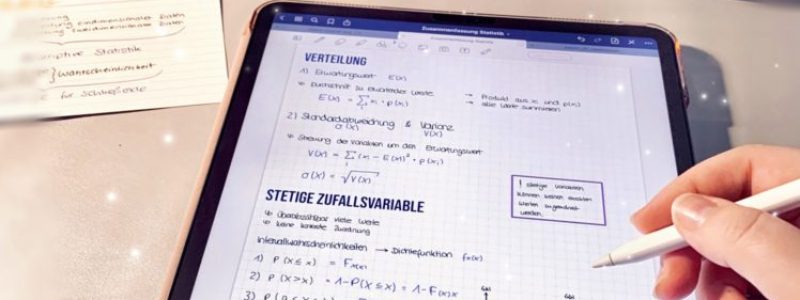 iPad auf einem Schreibtisch, Person schreibt digitales Notizen in einem digitalen Notizbuch in der App GoodNotes für Apple iPad